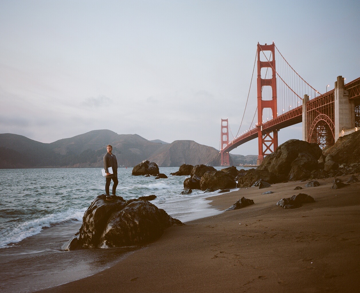 Mathias Mikkelsen on a rock at the beach below the Golden Gate Bridge, San Francisco